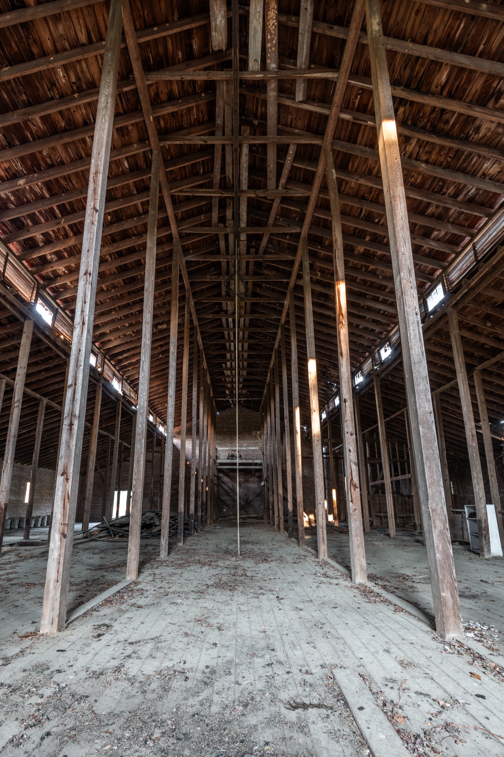 Full-height interior view of the 1931 Mule Barn, showing rows of tall timber posts, exposed roof rafters and a wooden floor
